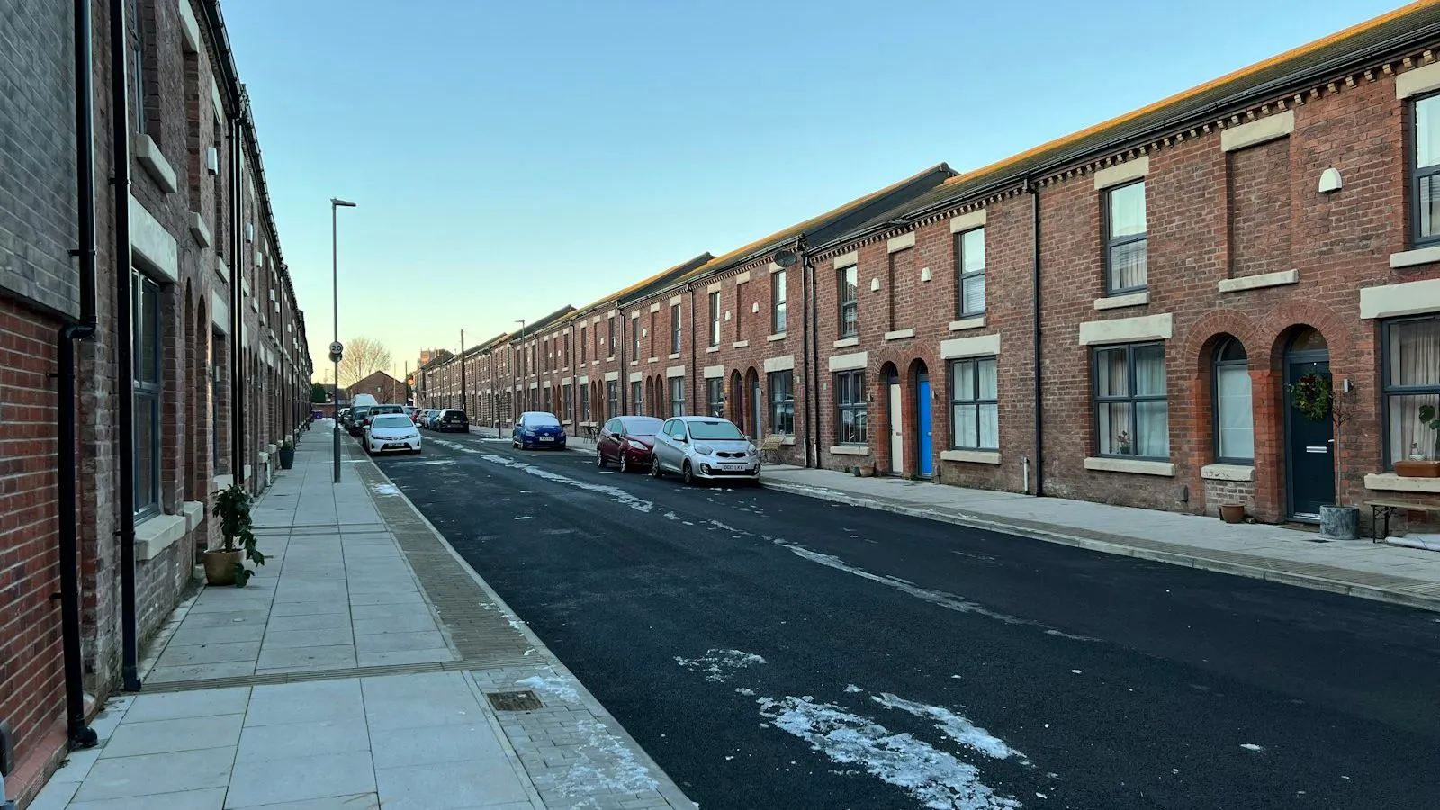 Street of red brick terraced houses with cars parked outside