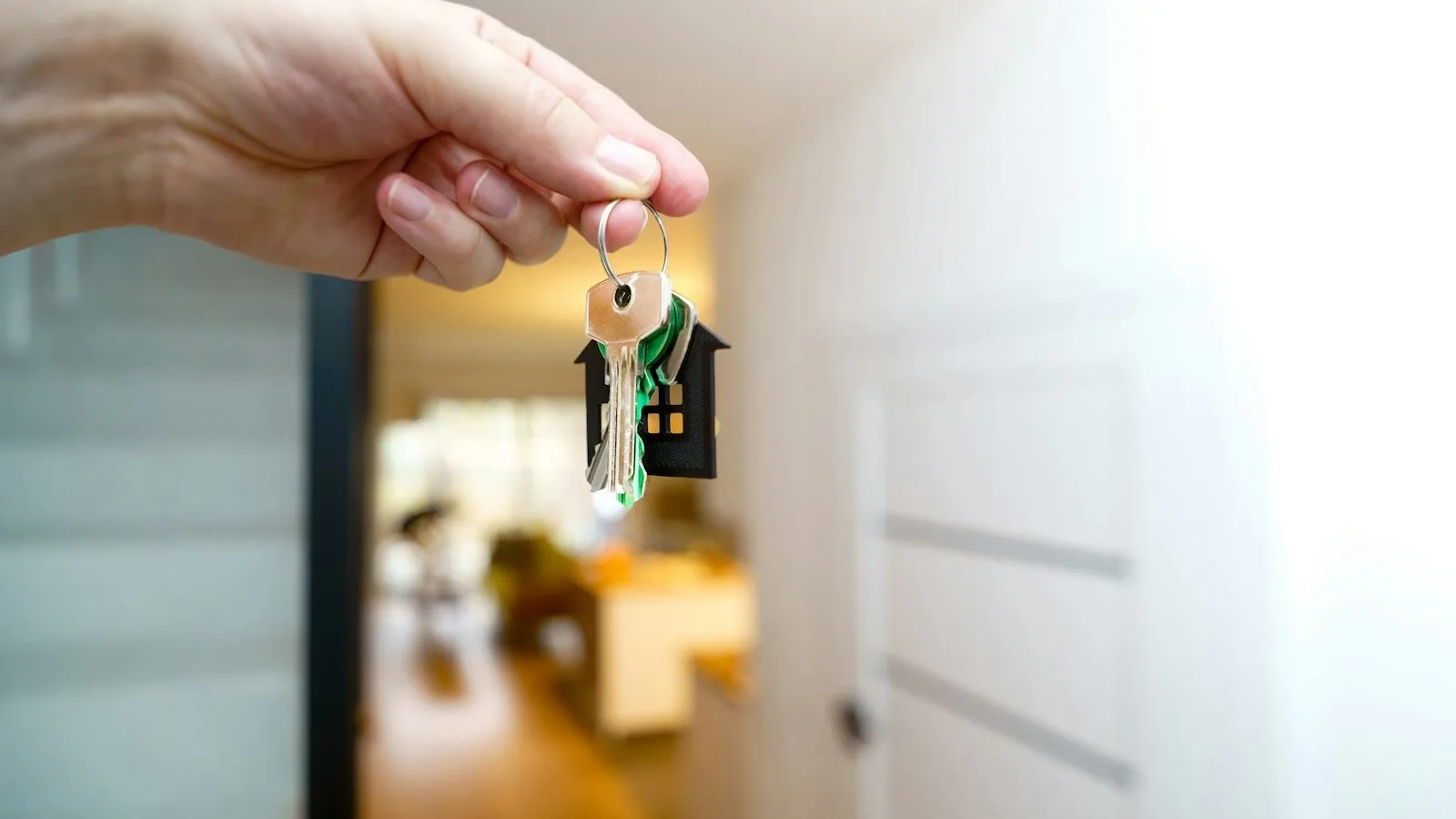 Hand holding a key at the front door of a house